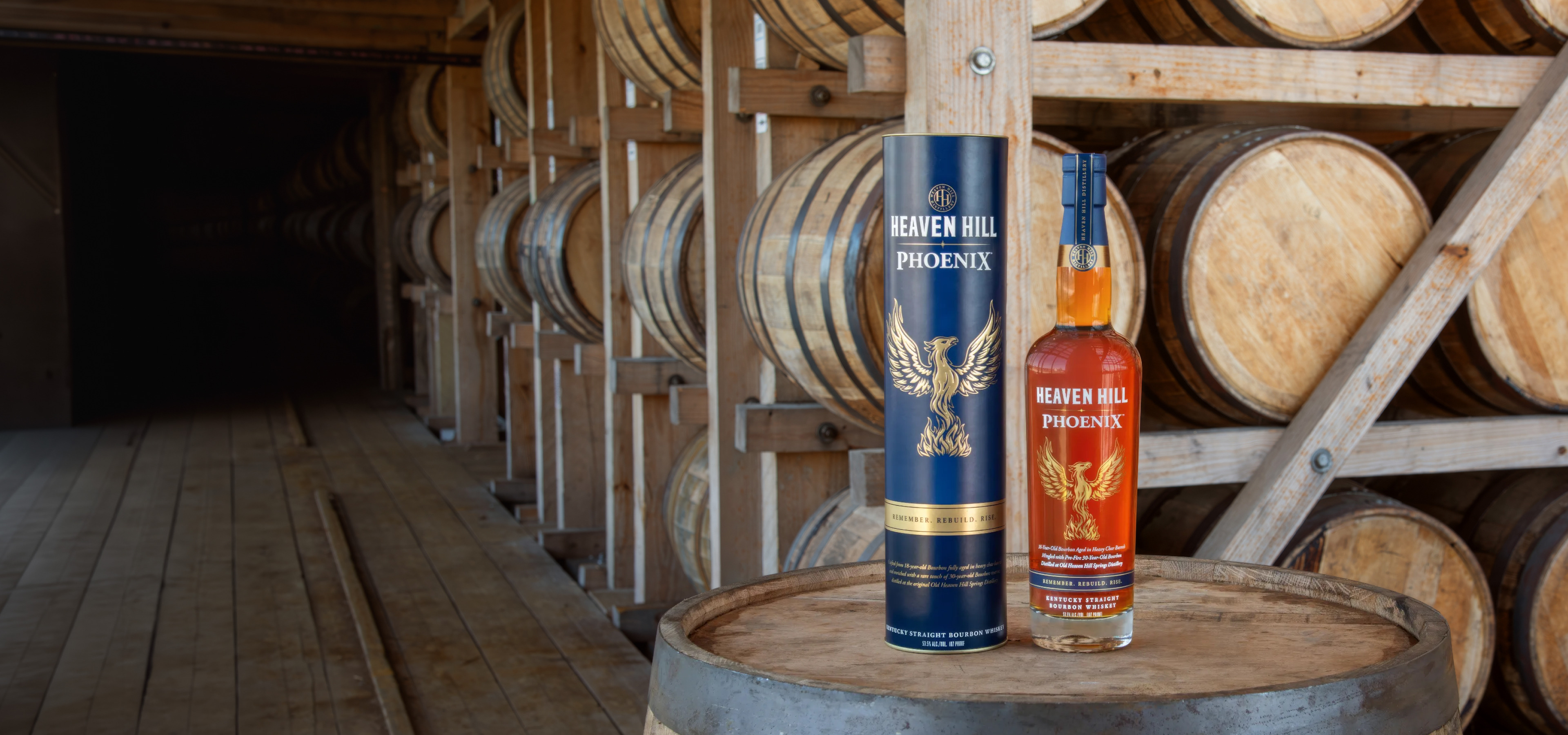 Heaven Hill Phoenix bottle and carton on a barrel in a rickhouse
